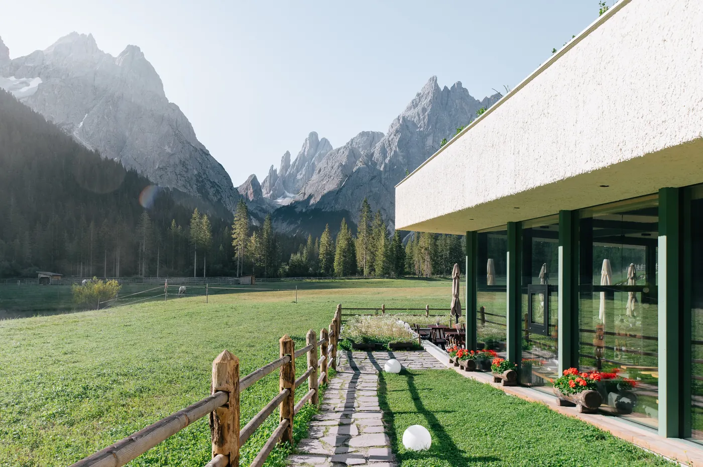 Glasfront und Terrasse des Bistro Bergsteiger mit Blick auf die Dolomitengipfel