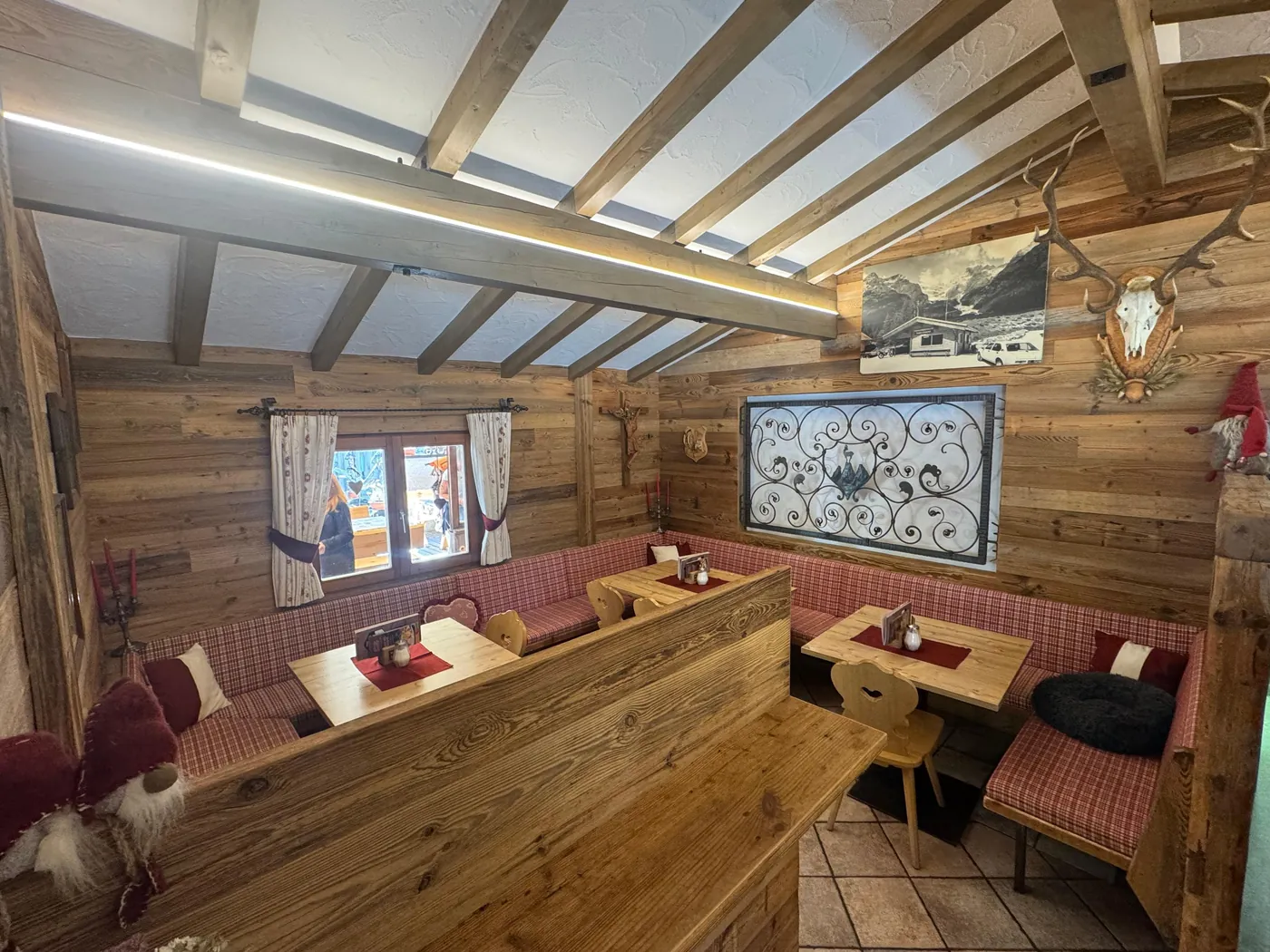 Stube der Fischleinbodenhütte mit Holzvertäfelung, karierten Sitzbänken und einem alten Foto der Hütte
